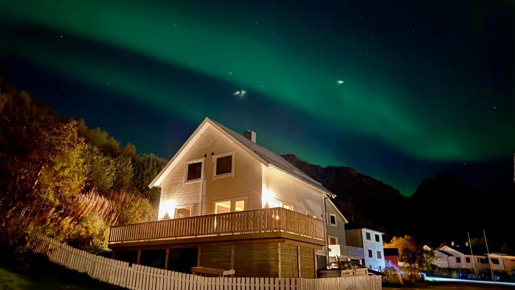 a house with the aurora in the sky at Sandersstua 2, luxury family apartment with private whirlpool in Stamsund in Vestvågøya