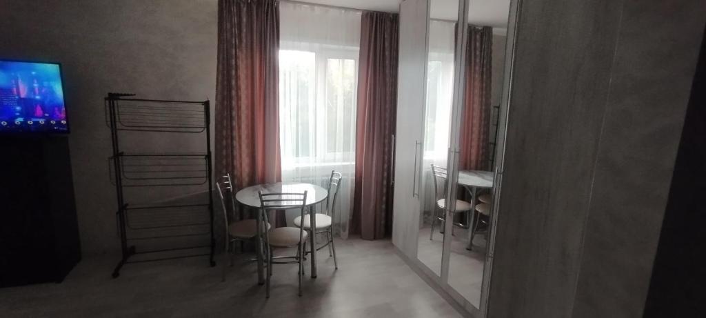 a dining room with a table and chairs and a window at Квартира посуточно Караганда in Karagandy