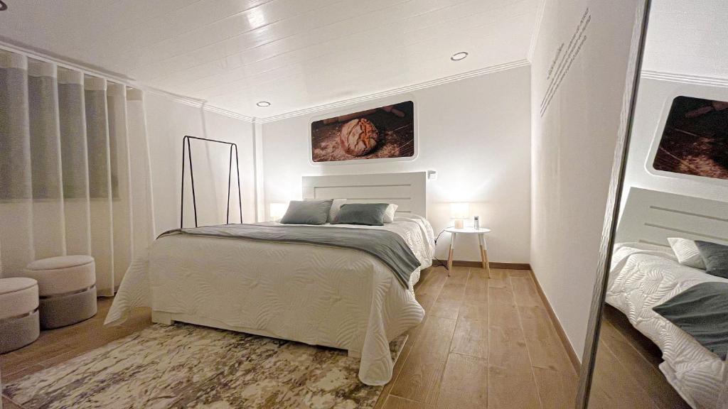 une chambre blanche avec un lit et un miroir dans l'établissement Casas Matias Nature - Boutique Mountain Houses com Pequeno-Almoço Continental - Serra da Estrela, Seia, à Carragozela