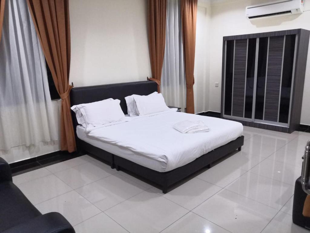 een slaapkamer met een bed met witte lakens en kussens bij USAS Resort, Kuala Kangsar in Kuala Kangsar