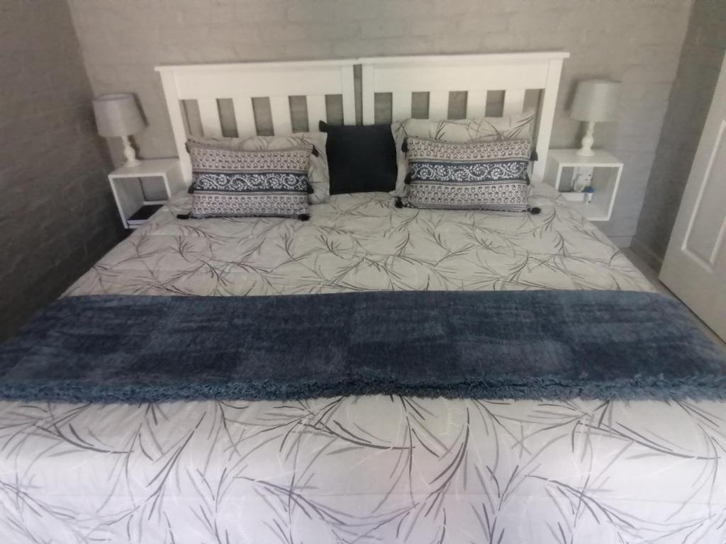 a large bed with a blue and white comforter and pillows at Petite Selfcatering Accommodation Struisbaai SA in Struisbaai