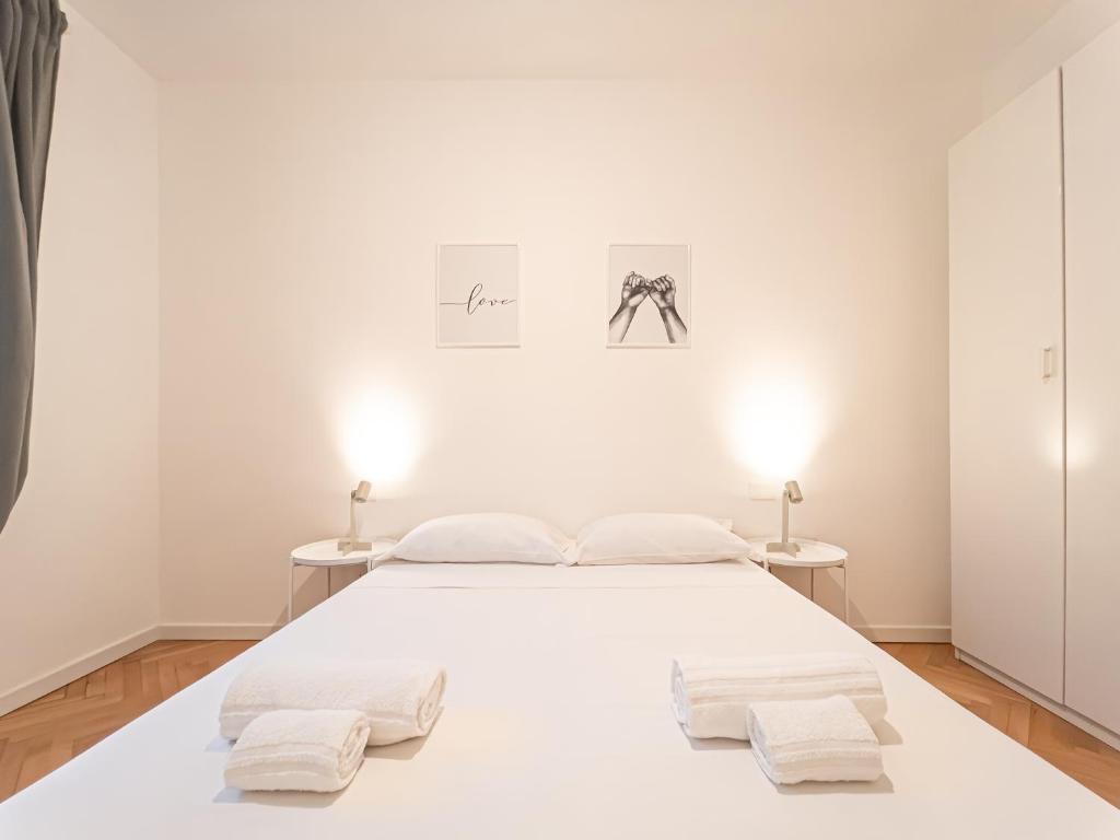 a white bedroom with a white bed and two tables at RRRapido Sant' Ambrogio Suites and Rooms - Via Olona in Milan