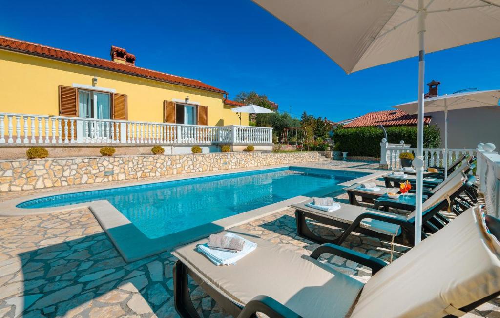 a house with a swimming pool with tables and umbrellas at Cozy Apartment In Rabac With Wifi in Rabac