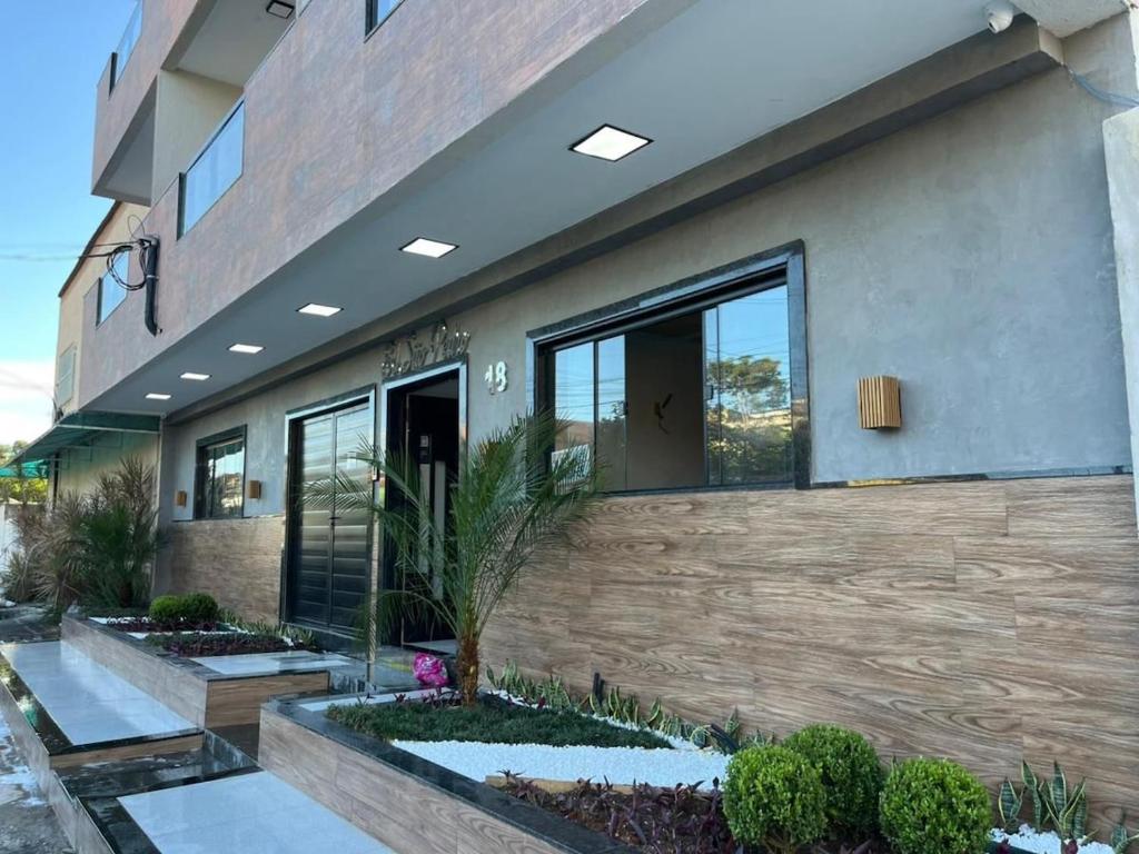 a building with windows and plants in front of it at Apart Hotel São Pedro Inn Caxias sup in Santa Cruz da Serra