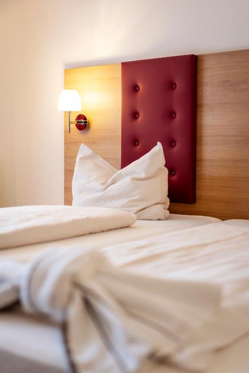a close up of a bed with white sheets and pillows at Hotel Rössle Berneck in Altensteig