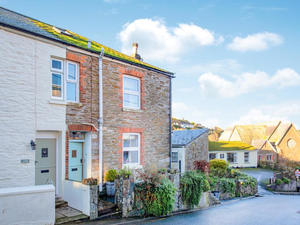 a brick house with a white door on a street at Tean in Polruan