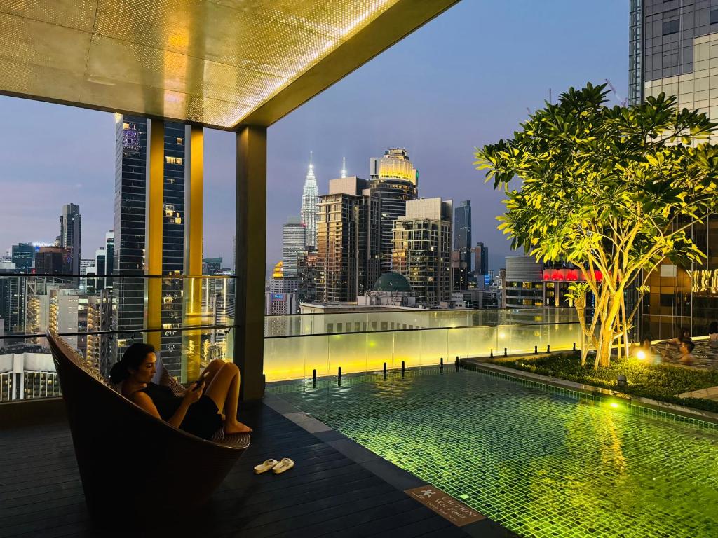 two women sitting in a hammock on a rooftop overlooking a city at Axon Residence KL in Kuala Lumpur