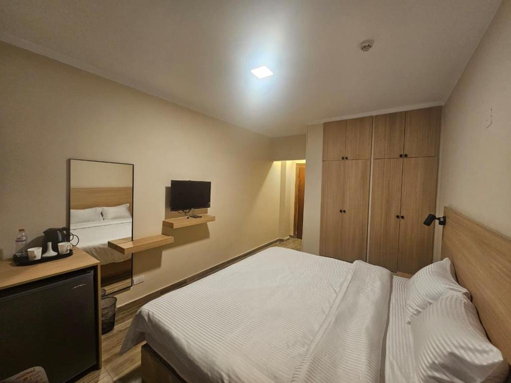 カイロにあるOasis Heliopolis Hotel-فندق أوازيس هليوبوليسの白いベッドと鏡のある寝室