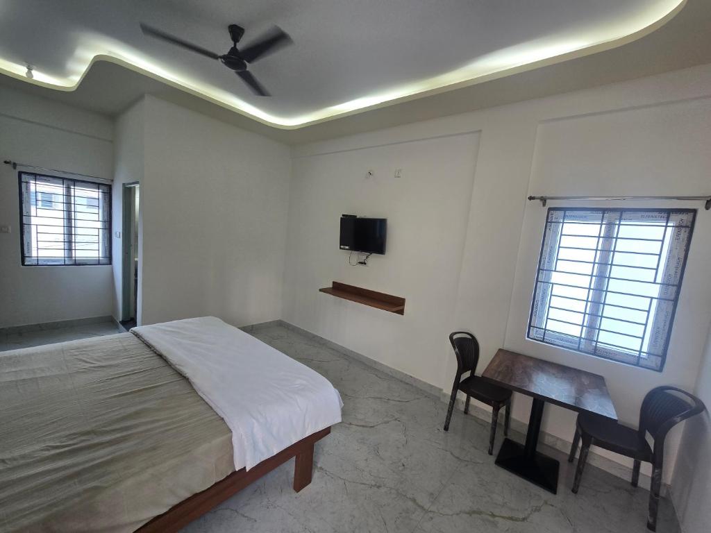 a bedroom with a bed and a desk and a tv at patelru comforts in Nelamangala