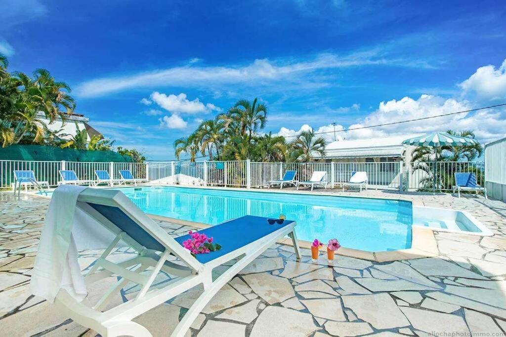 une piscine avec une chaise longue à côté d'une piscine dans l'établissement Studio de l'Anse Mitan, à Les Trois-Îlets