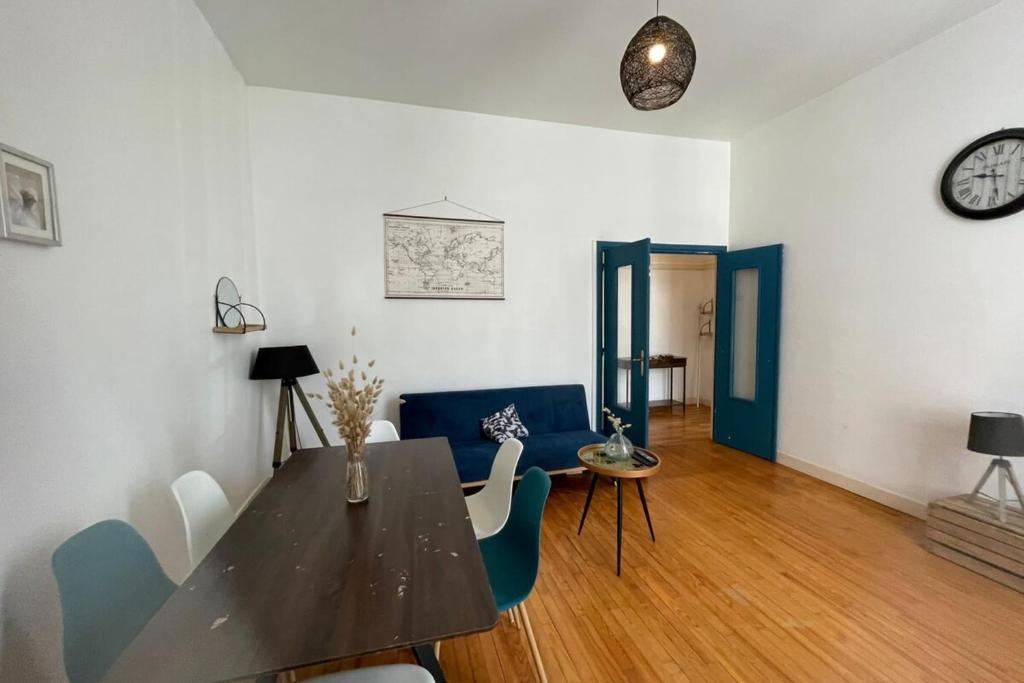 a living room with a table and chairs and a clock at Les Pieds dans le Bassin in Le Havre