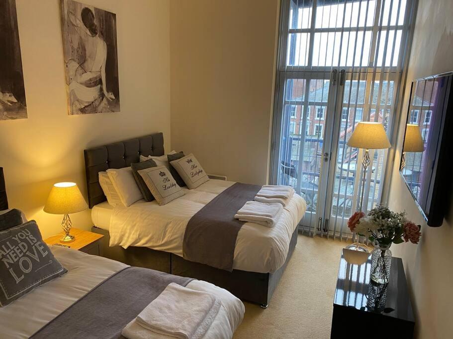 a bedroom with two beds and two lamps and windows at The Waterfront Suite in Southport