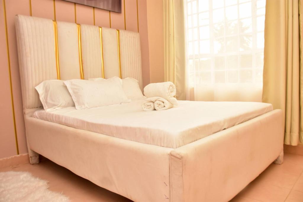 un grand lit blanc dans une chambre avec une fenêtre dans l'établissement Comfy one bedroom Eldoret town, à Eldoret