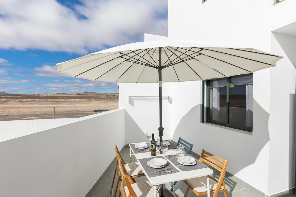 a table and chairs with an umbrella on a balcony at Home2Book Sunny Terrace Getaway Puerto Lajas in Puerto de las Lajas