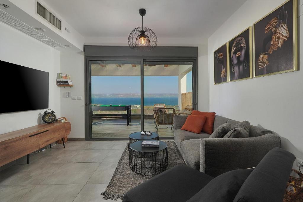 a living room with a couch and a flat screen tv at דירת נופש נוף לכנרת in Migdal