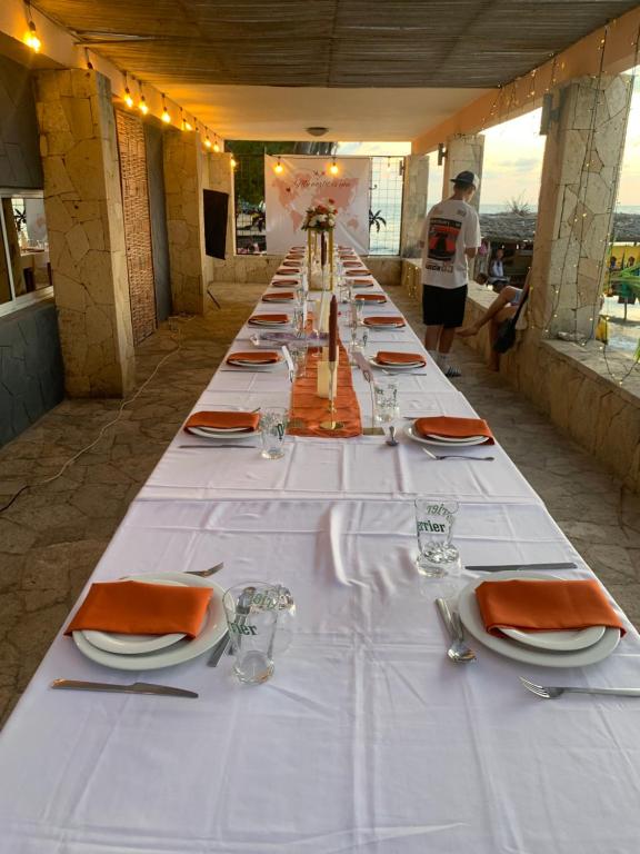 une longue table avec des nappes blanches et des serviettes orange dans l'établissement Ifaty Beach Club Resort, à Ifaty