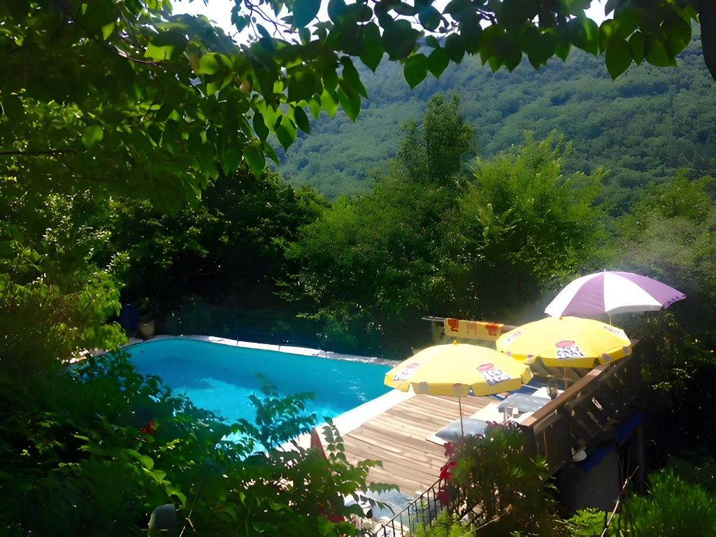 una piscina con dos sombrillas y una terraza con piscina. en Gite Du Haut - À La Rouquette, en Saint-Privat
