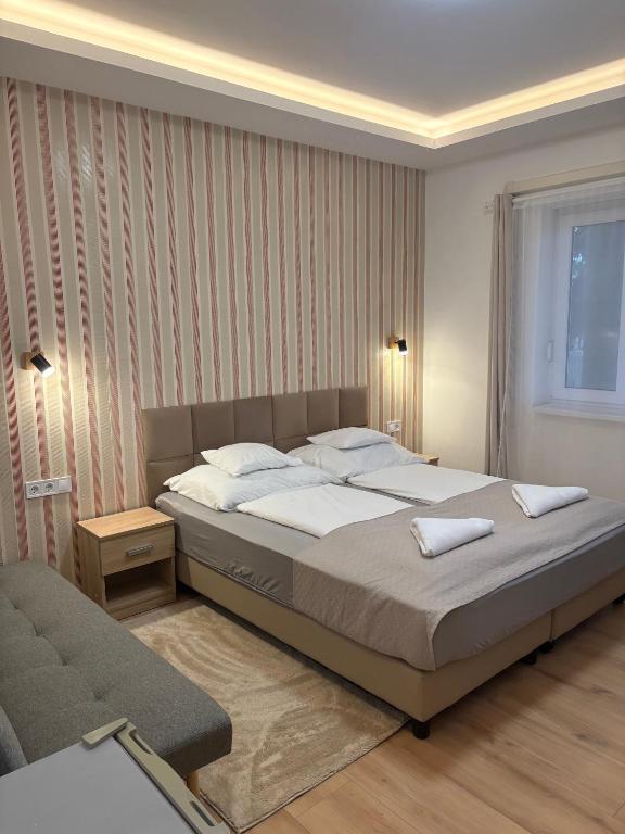 a bedroom with a large bed and a chair at Landing Rooms Apartman in Üllő