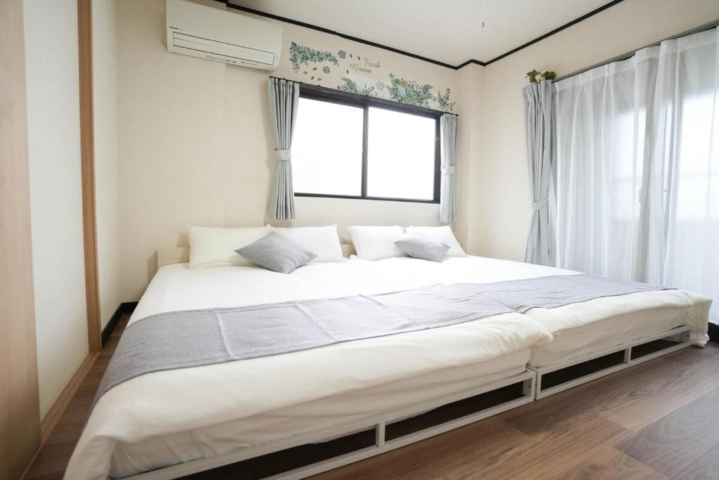 a large bed in a room with a window at 302 Grand Maison konohana 予約制駐車場,USJや海遊館に最適,駅から徒歩6分 in Osaka