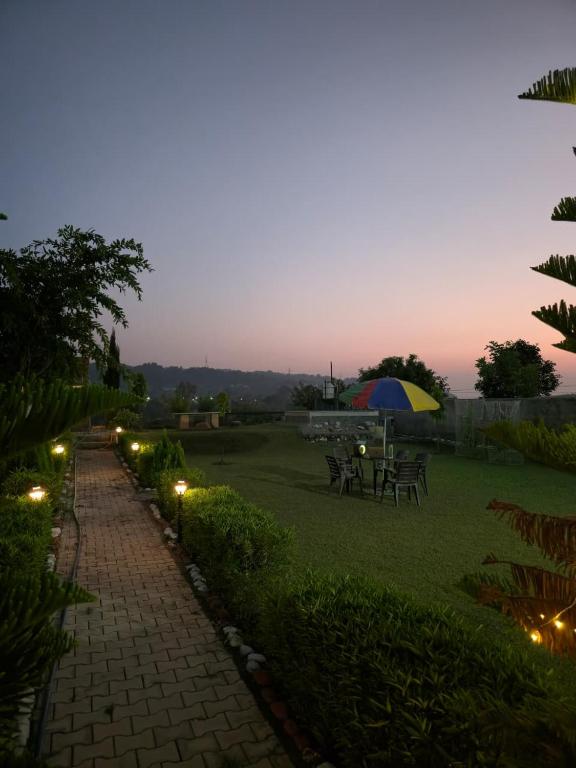 a patio with tables and an umbrella and lights at H M farm in Surajpur