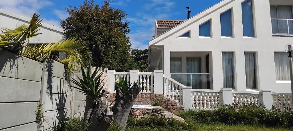 a white house with a white fence and a palm tree at Solomon's Nest in Glencairn