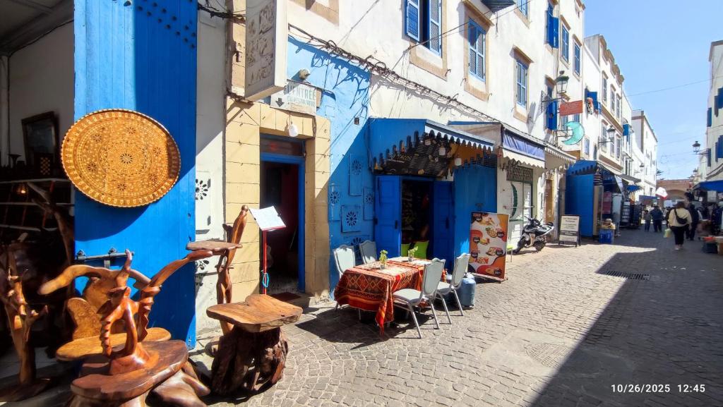 a street with a table and chairs in front of a blue building at Riad Bladi Essaouira in Essaouira