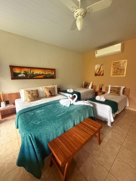 a bedroom with two beds and a bench in it at Apt Flat 225 Condomínio Pedra do Rodeadouro in Bonito