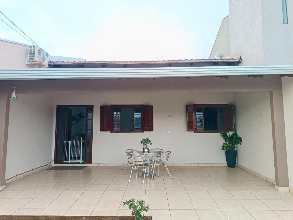 a patio with chairs and a table in front of a house at Casa Completa em Foz do Iguaçu in Foz do Iguaçu