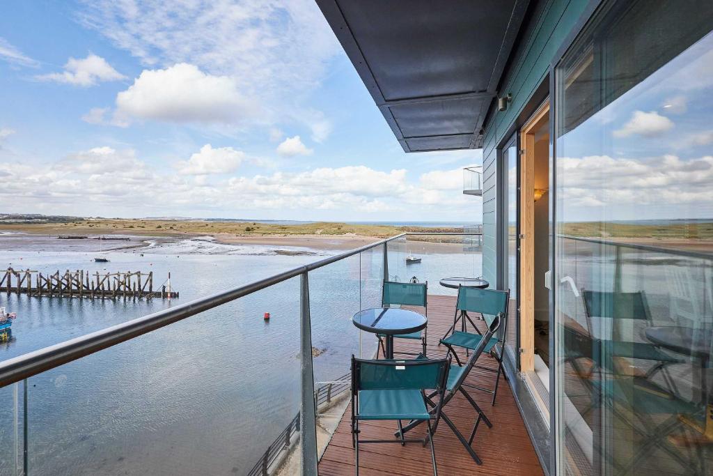 een balkon met stoelen en een tafel en water bij Host & Stay - Becalmed in Amble