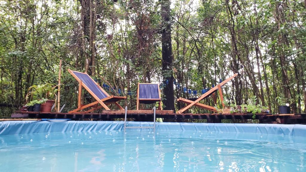 two chairs sitting next to a swimming pool at Espacio Las Abejas Cabaña Las Abejas in Tigre