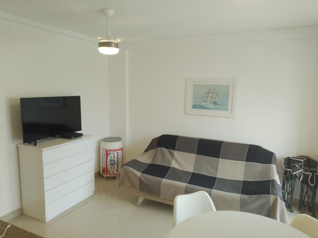 a white room with a bed and a tv at Praia Mansa Caioba in Matinhos