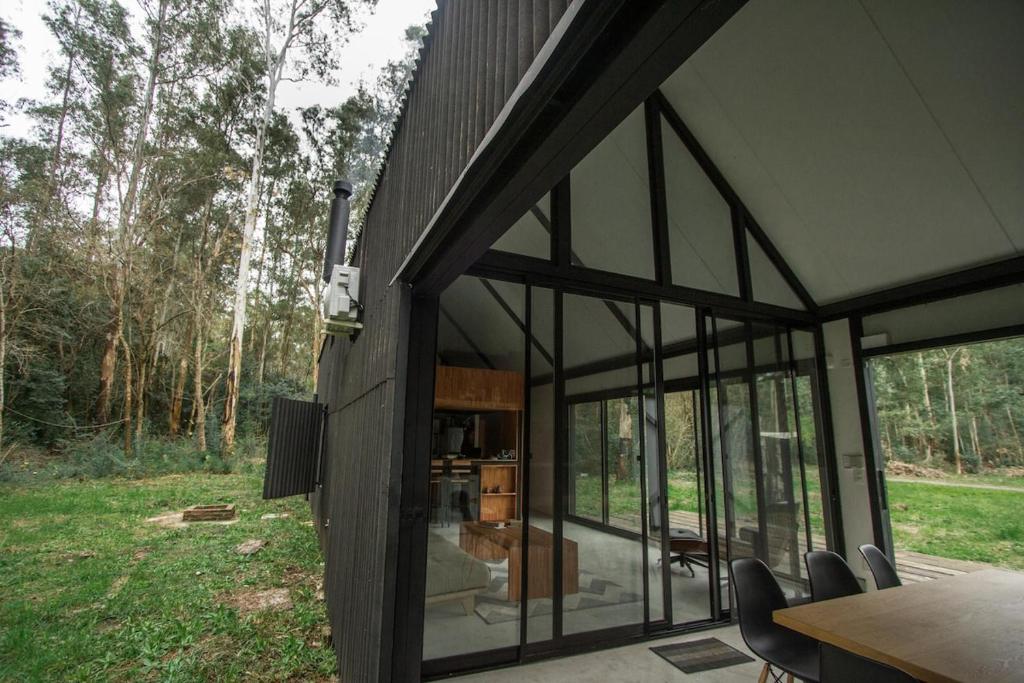 ein Haus mit Glastüren, einem Tisch und Stühlen in der Unterkunft Cabaña estilo escandinavo in Santa Ana