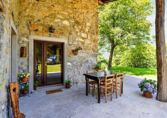 a table and chairs outside of a stone house at House in the Shambhalla Forest in Esmate