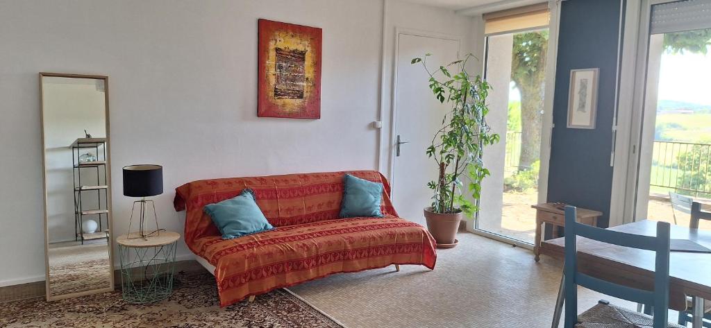 a living room with a red couch with blue pillows at studio indépendant dans maison à la campagne in Lagor