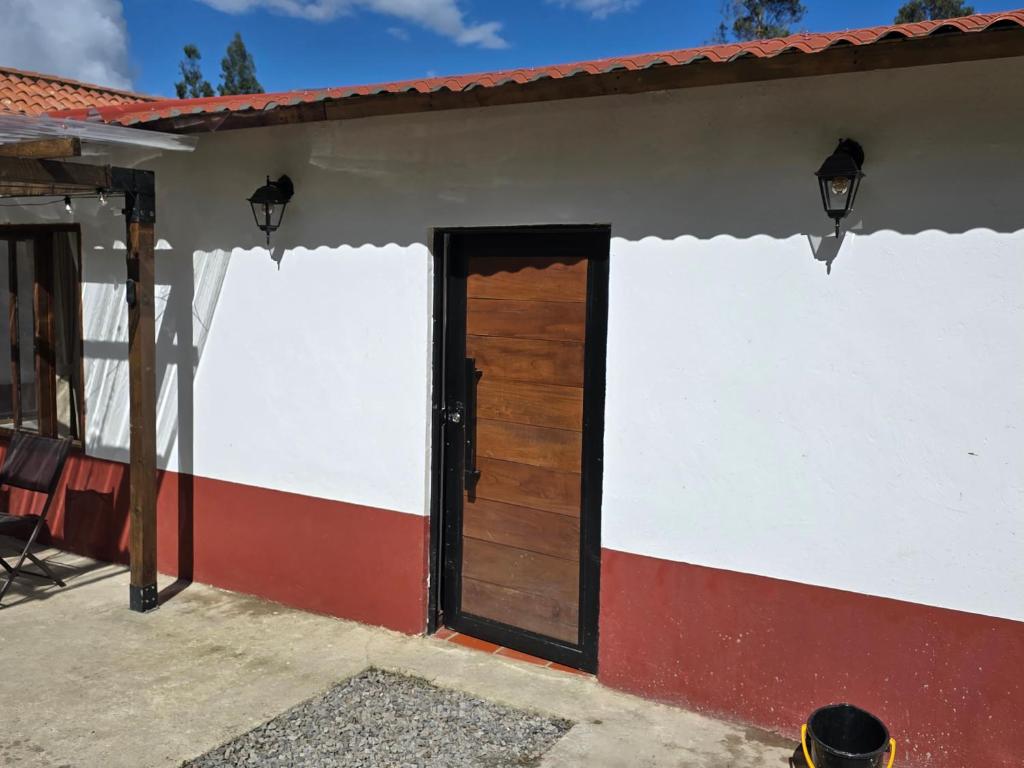 a white and red house with a wooden door at Finca santa helena in Machetá