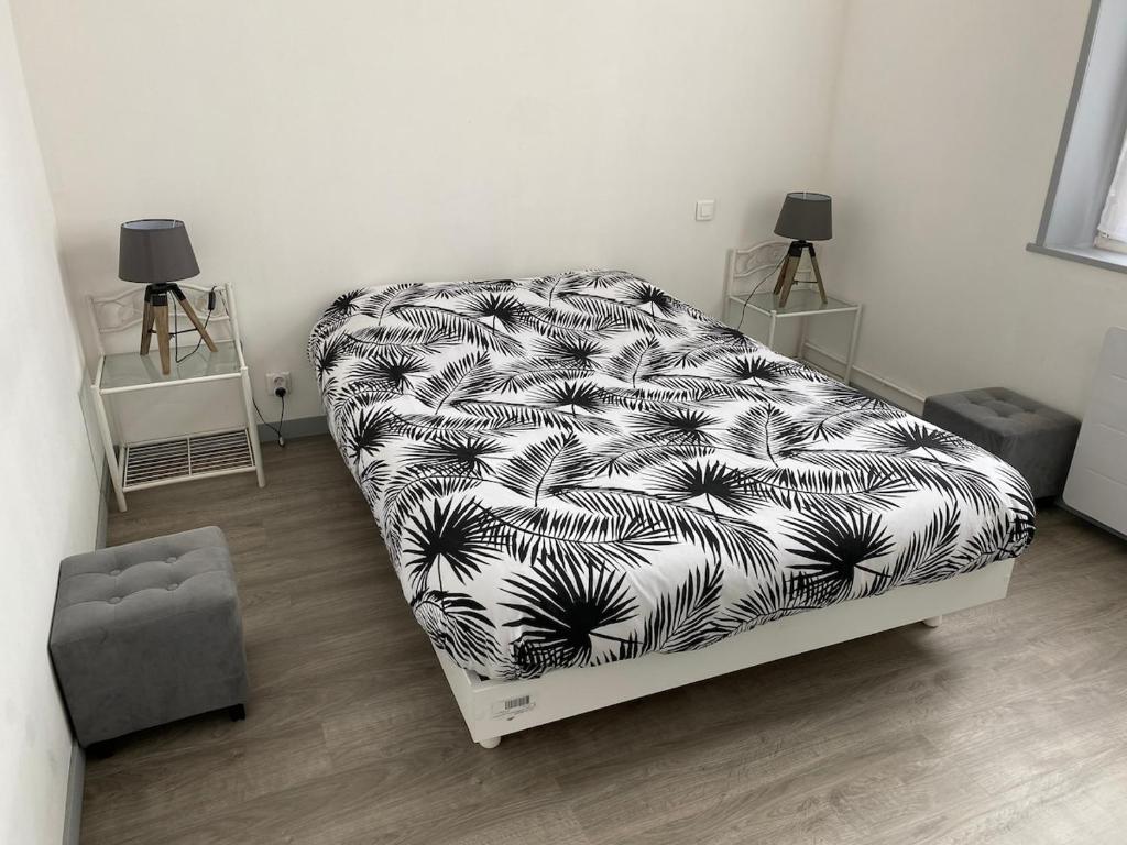 ein Schlafzimmer mit einem Bett mit einer schwarzen und weißen Decke in der Unterkunft Apt Baie de Somme en centre ville 200m de la plage in Cayeux-sur-Mer