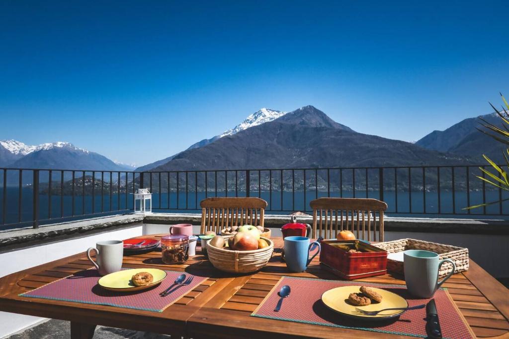 a table with food on top of a balcony with mountains at Casa Sorel : Attico Lago & Pool in Pianello Del Lario