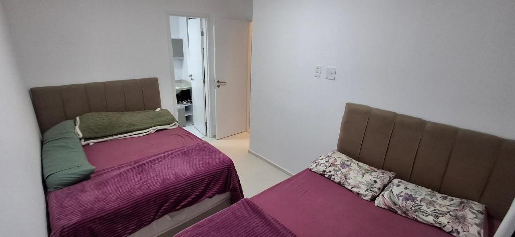 2 Betten in einem kleinen Zimmer mit violetter Bettwäsche in der Unterkunft Apartamento 2 quartos na orla de Aracaju 2 in Aracaju