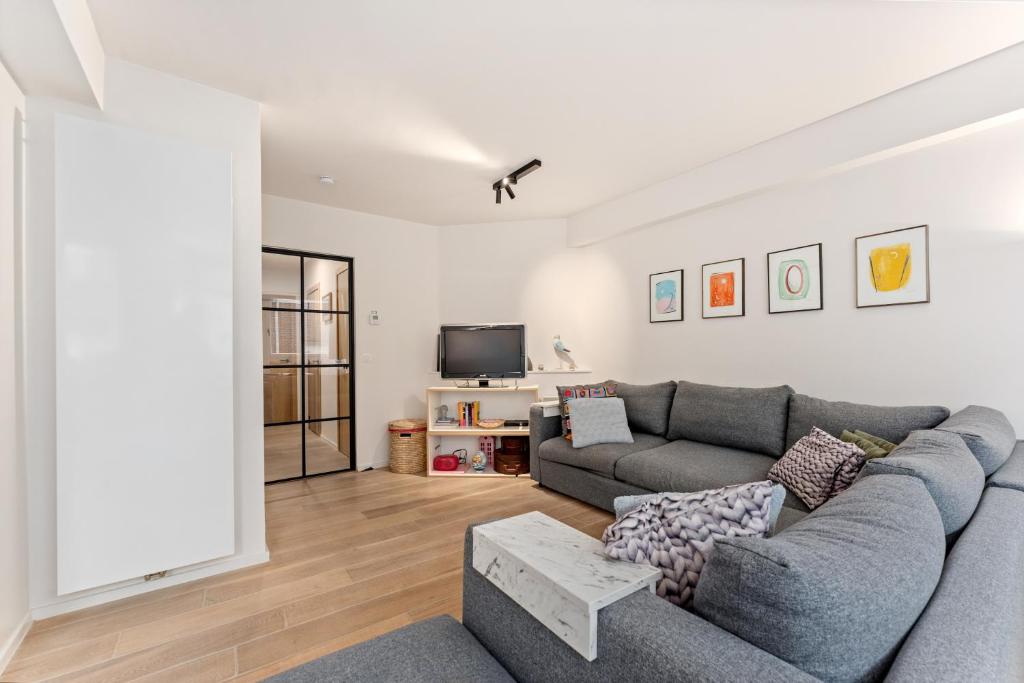 a living room with a couch and a tv at Sparrenduin - Compact en cosy app aan golf De Haan in De Haan