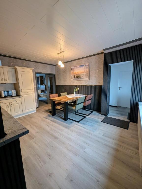 a dining room with a wooden table and a kitchen at Ferienwohnung Landkajüte in Twist
