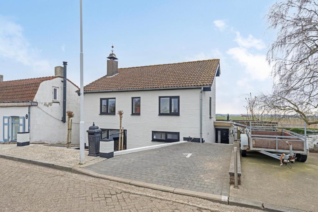 une maison blanche avec un camion garé devant elle dans l'établissement Graafjansdijk B Vakantiehuis met 3 slaapkamers net over de Belgische grens, à Westdorpe
