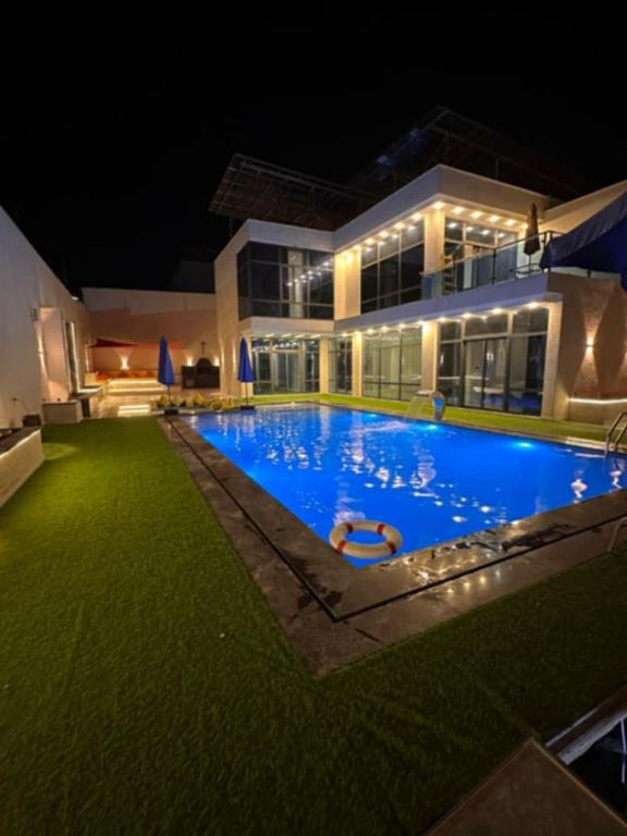 a large swimming pool in front of a building at night at las vegas villa in Ath Thughrah