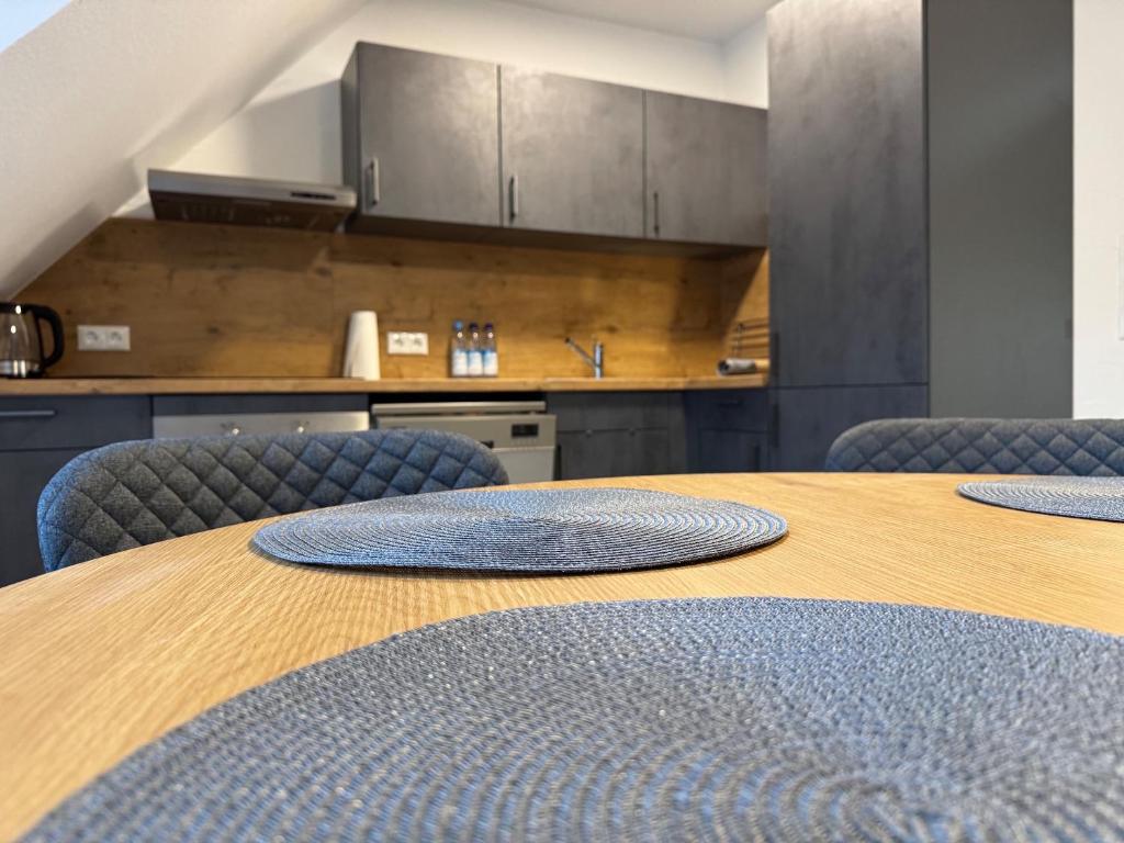 einen Holztisch mit blauen Stühlen und eine Küche in der Unterkunft Ferienwohnung Aischgrund in Lonnerstadt