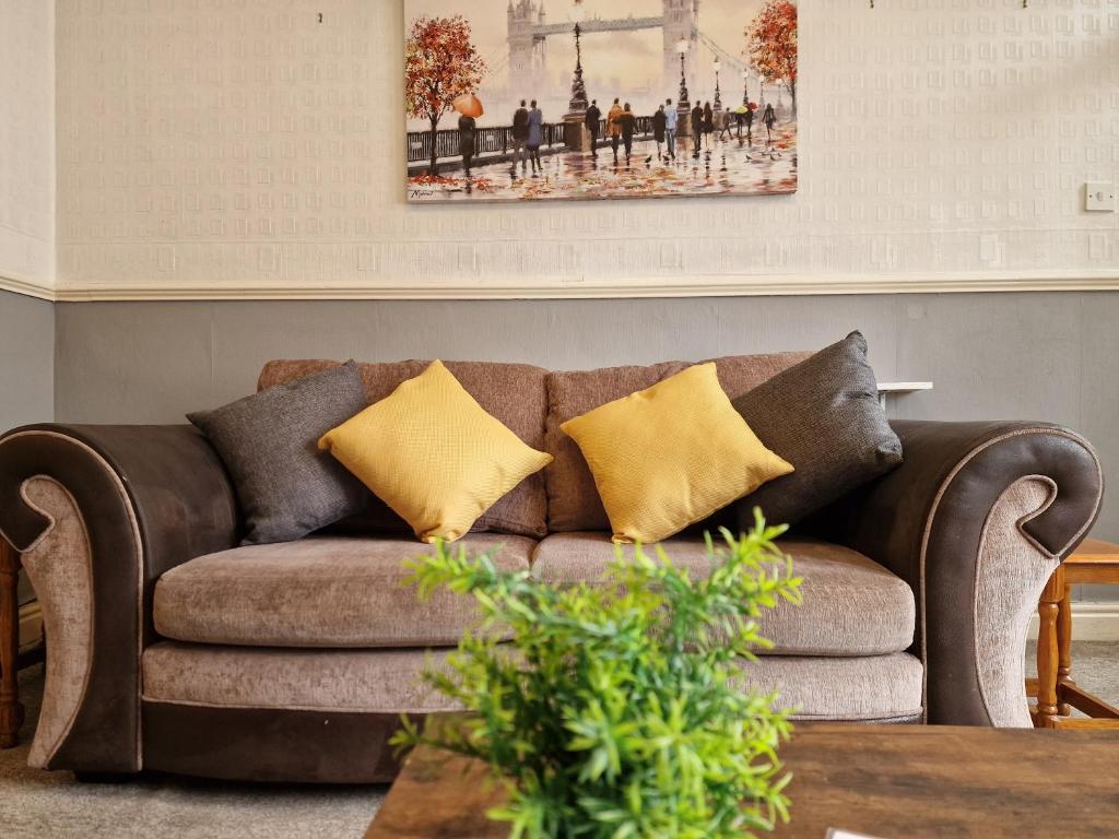 a brown couch with yellow pillows in a living room at Devon St - Cozy home, Free easy parking! in Hull