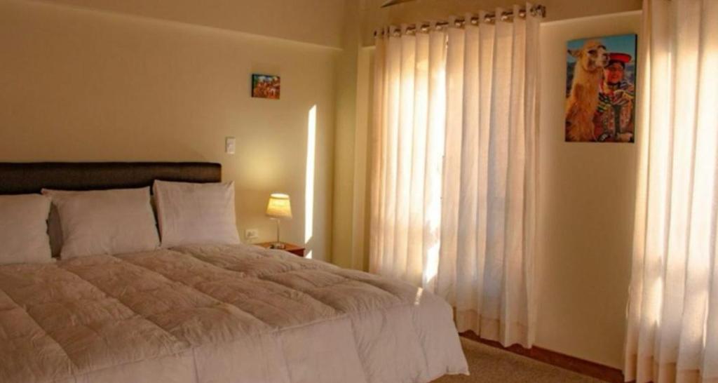 Un dormitorio con una cama y una ventana con cortinas. en Veronica lookout Hotel, en Urubamba