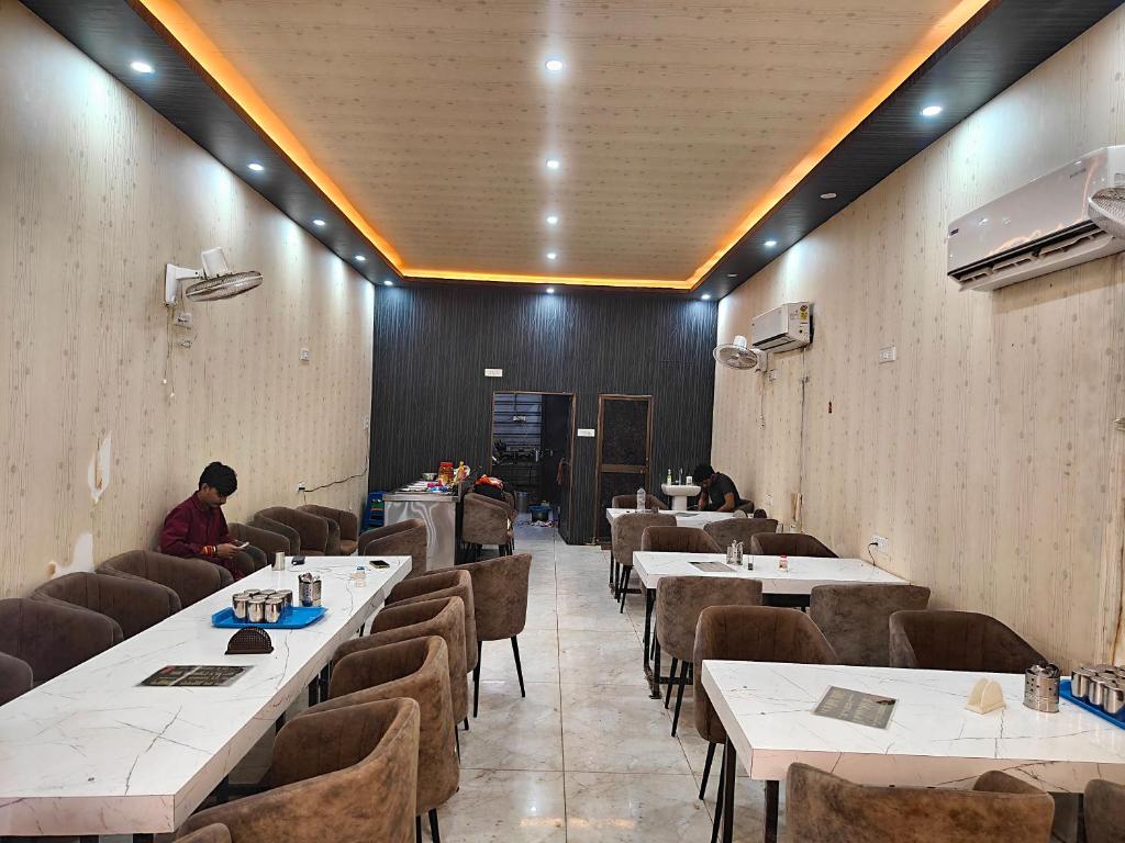 a restaurant with tables and chairs and a person sitting in a room at Krishna guest House - 600 meter away from ram mandir in Ayodhya