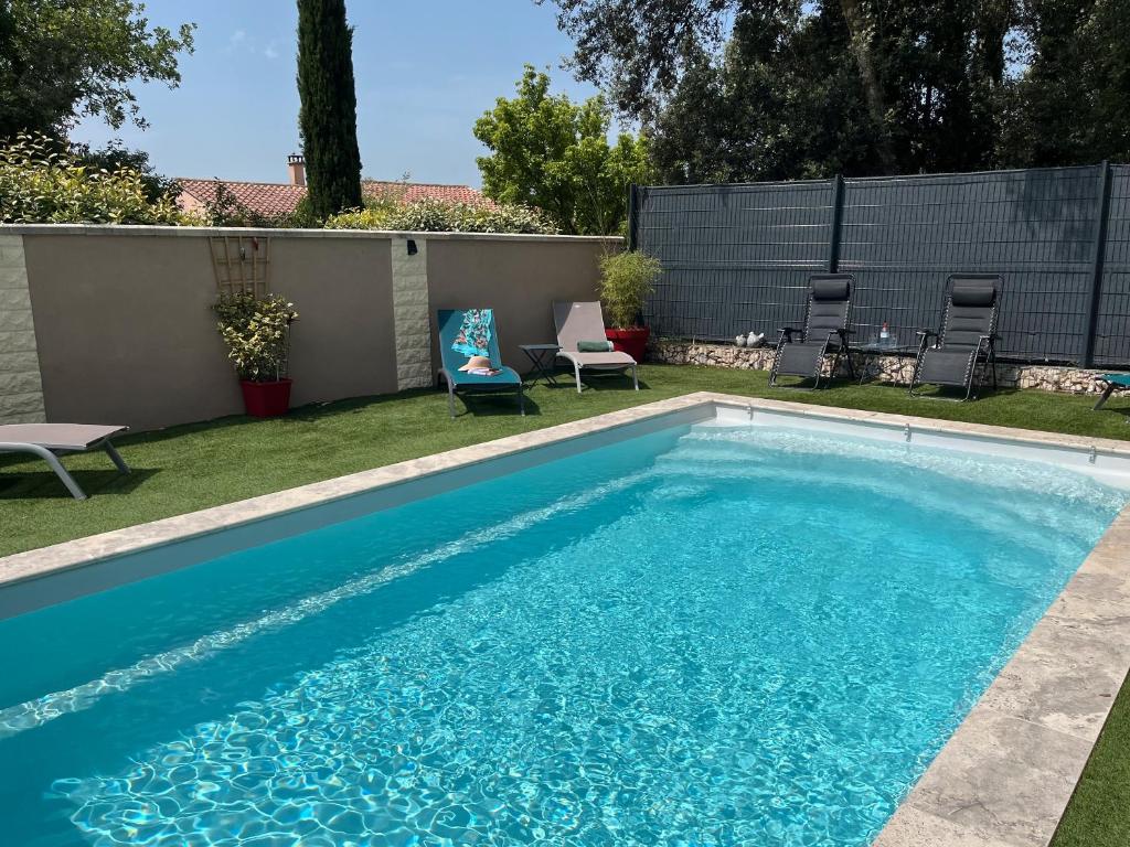 una piscina con acqua blu in un cortile di La Petite Maison a Bédoin