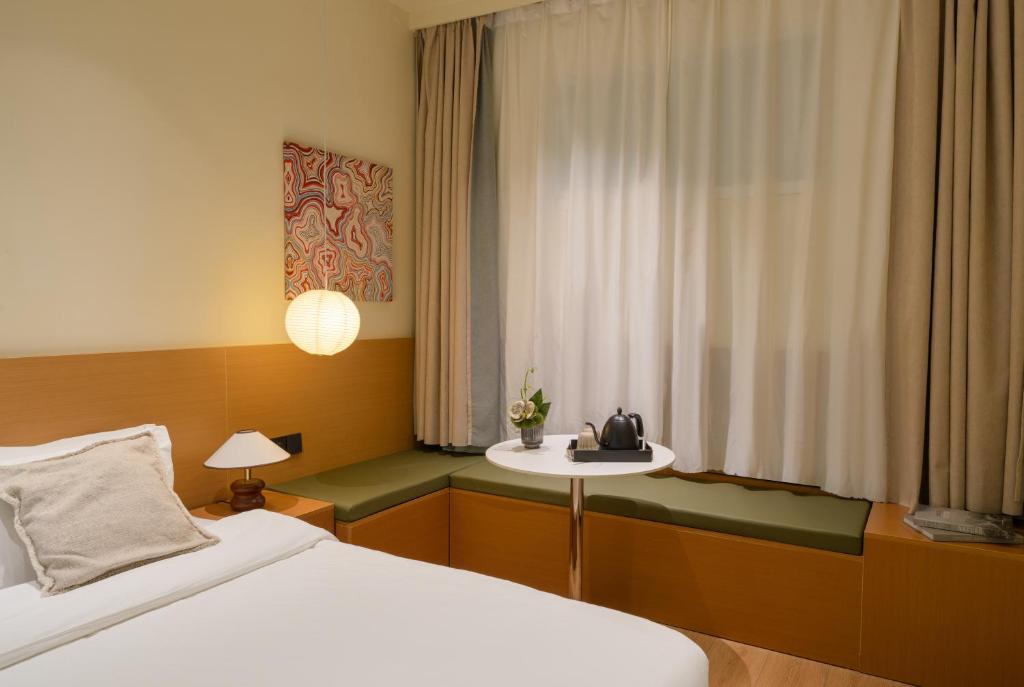 a bedroom with a bed and a table and a window at Xiamen Evening Breeze Hotel in Xiamen