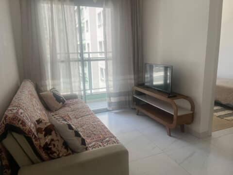 een woonkamer met een bank en een tv bij Apartamento de 2 quartos, com piscina e há 10 km de copacabana in Rio de Janeiro