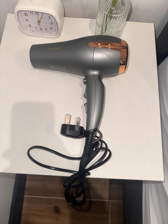 a hair dryer on a white table with a clock at Luxury Apartment Close to Elstree & Borehamwood Station in Borehamwood